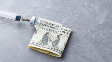 Şırınga aşısı ve bir dolar. Aşı şişesi ve gri arka planda para. Aşı satın alma konsepti. Üst Manzara. Boşluğu kopyala