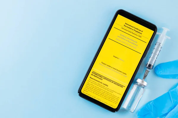 Yellow international certificate of vaccination, vaccine vial and syringe. Vaccine bottle, syringe and smartphone with vaccination certificate. Vaccination concept