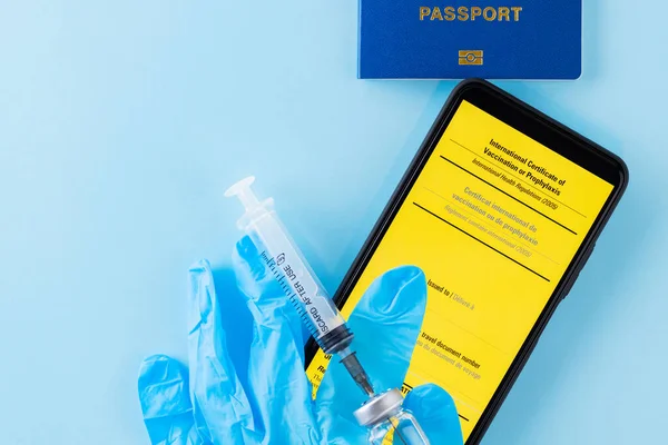 Vaccination concept. Yellow international certificate of vaccination, vaccine vial and syringe. Vaccine bottle, syringe and passport on a blue background. Immunity passport