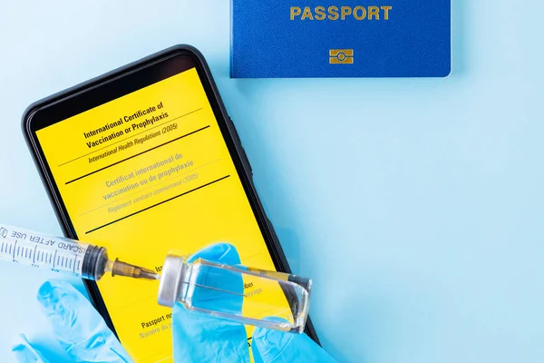 Vaccination concept. Yellow international certificate of vaccination, vaccine vial and syringe. Vaccine bottle, syringe and passport on a blue background. Immunity passport