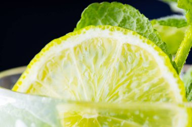 Mojito, karanlık arka planda yakın plan. Buzlu limon dilimi ve naneli mojito. Limonlu, naneli ve buzlu içecek. Yazın soğuk içecek.