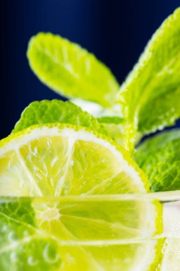 Mojito, karanlık arka planda yakın plan. Buzlu limon dilimi ve naneli mojito. Limonlu, naneli ve buzlu içecek. Yazın soğuk içecek.