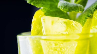 Mojito, karanlık arka planda yakın plan. Buzlu limon dilimi ve naneli mojito. Limonlu, naneli ve buzlu içecek. Yazın soğuk içecek.