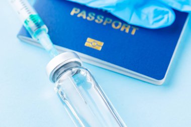 Aşı konsepti. Uluslararası biyometrik aşı pasaportu, aşı şişesi ve şırınga. Aşı şişesi, şırınga ve mavi arka planda pasaport. Dokunulmazlık pasaportu