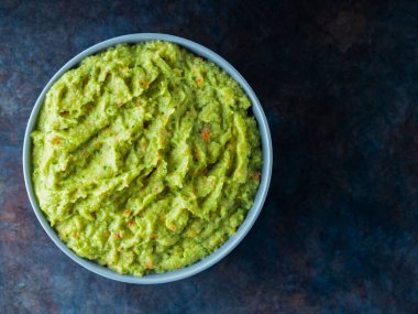 Arka planda gri bir kasede guacamole. Bir kase avokado guacamole sosu ve taze malzemeler. Uzayı kopyala Üst görünüm