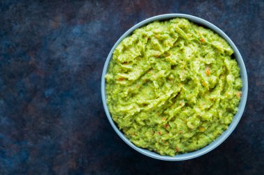 Arka planda gri bir kasede guacamole. Bir kase avokado guacamole sosu ve taze malzemeler. Uzayı kopyala Üst görünüm