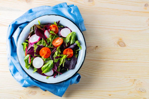 Sebze salatası ve mavi peçetede yeşillik karışımı. Kiraz domatesli sağlıklı salata, turp ve karışık salata. Uzayı kopyala Düz yatıyordu