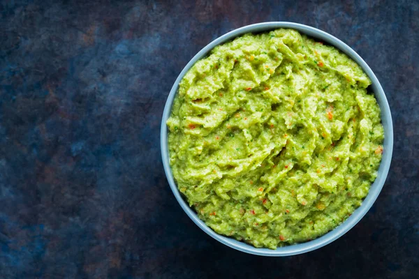 Arka planda gri bir kasede guacamole. Bir kase avokado guacamole sosu ve taze malzemeler. Uzayı kopyala Üst görünüm