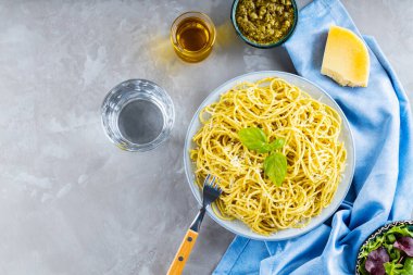 Soslu makarna ve sebze salatası. Pesto soslu spagetti ve gri arka planda taze fesleğen. Uzayı kopyala Üst görünüm
