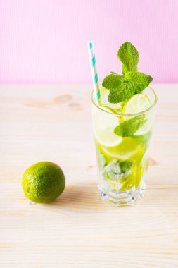 Uzun bardakta yaz mojito kokteyli. Pembe arka planda mojito kokteyli. Limonlu, naneli ve buzlu içecek. Moda içeceği