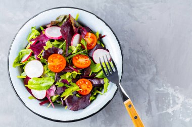 Gri arka planda yeşillik karışımı salata. Kiraz domatesli, turplu ve karışık salatalı sağlıklı sebze salatası. Boşluğu kopyala