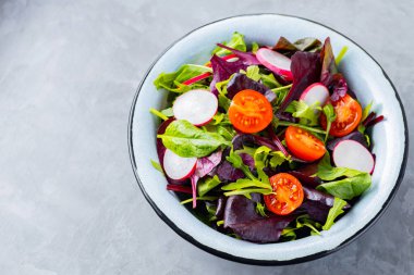 Gri arka planda yeşillik karışımı salata. Kiraz domatesli, turplu ve karışık salatalı sağlıklı sebze salatası. Boşluğu kopyala