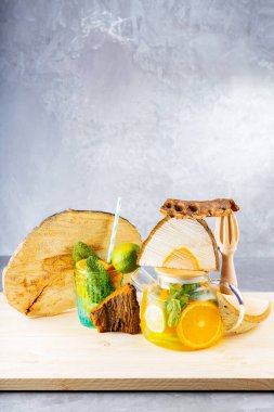 Limonata, limon, portakal ve nane yapraklarından oluşan şeffaf bir çaydanlık. Naneli buzlu çay ve odun parçaları. Yaratıcı bileşim