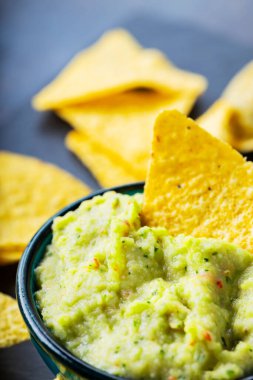 Arka planda guacamole ve cips. Tahtada mısır cipsi ve guacamole sosu. Yakın plan. Seçici odak