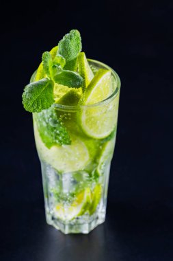 Karanlık bir arka planda mojito kokteyli. Limonlu, naneli ve buzlu içecek. Yaz kokteylinin yakın çekimi