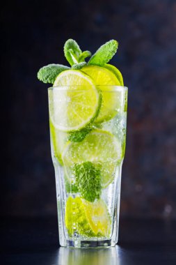 Karanlık bir arka planda mojito kokteyli. Limonlu, naneli ve buzlu içecek. Yaz kokteylinin yakın çekimi