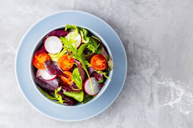 Kiraz domatesli, turplu ve karışık salatalı sağlıklı sebze salatası. Gri arka planda yeşillik karışımı vejetaryen salatası. Paleo diyet konsepti. Uzayı kopyala Üst görünüm