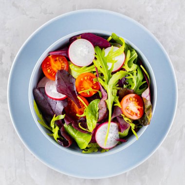 Kiraz domatesli, turplu ve karışık salatalı sağlıklı sebze salatası. Gri arka planda yeşillik karışımı vejetaryen salatası. Paleo diyet konsepti. Uzayı kopyala Üst görünüm