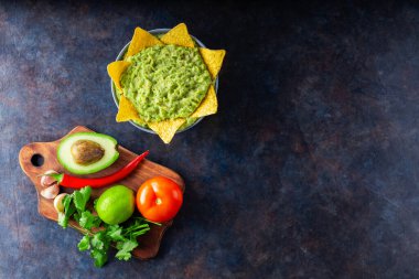 Malzemeli guacamole ve nachos tortilla cipsi. Arka planda biber, limon ve mısır cipsli avokado sosu. Uzayı kopyala Üst görünüm