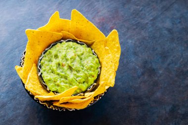 Geleneksel Meksika soslu guacamole ve kil kasesinde tortilla cipsi. Koyu arkaplanda cipsli bir kase guacamole. Uzayı kopyala Üst görünüm