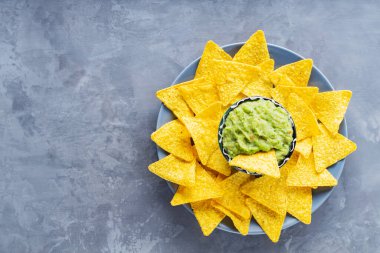 Meksika soslu guacamole ve bir tabak nacho cipsi. Gri arka planda cipsli bir kase guacamole. Uzayı kopyala Düz yatıyordu