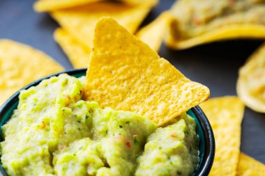 Arka planda guacamole ve cips. Tahtada mısır cipsi ve guacamole sosu. Yakın plan. Seçici odak