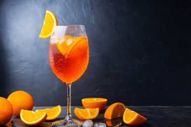 Aperol sprey kokteyli ve bar aksesuarları. İtalyan aperol sprey kokteyli ve koyu arkaplanda dilimlenmiş portakal. Yaz kokteyli aperol spreyini tahtaya serptim.
