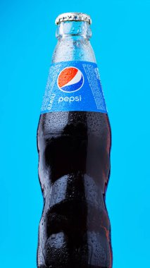 DNIPRO, UKRAINE - 16 Ağustos 2021: Mavi zemin üzerinde su damlaları olan cam şişe Pepsi