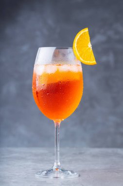 Kokteyl aperol spreyi. Gri arka planda bir bardak aperol spreyi. Bir dilim portakallı İtalyan yaz kokteyli.