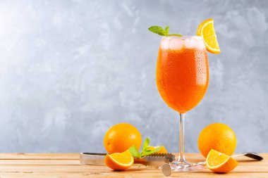 Bar aksesuarlarıyla birlikte Aperol sprey kokteyli. İtalyan aperol sprey kokteyli ve gri arka planda dilimlenmiş portakal. Kokteyl aperol spreyi ve taze nane.