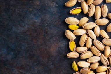Koyu arkaplanda kavrulmuş fıstık. Pistachio - sağlıklı vejetaryen protein besleyici gıdalar. Sağlıklı atıştırmalıklar. Uzayı kopyala Üst görünüm