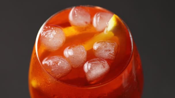 Aperol spritz cocktail close-up. Spoon mixes beverage. Glass of summer orange cocktail on black background. 4k — Stock Video