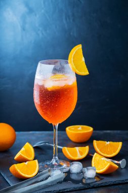 Aperol sprey kokteyli ve bar aksesuarları. İtalyan aperol sprey kokteyli ve koyu arkaplanda dilimlenmiş portakal. Yaz kokteyli aperol spreyini tahtaya serptim.