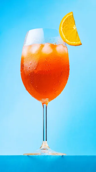 Aperol Spritz鸡尾酒配一片橙子一杯蓝色背景的鸡尾酒开胃酒 意大利夏季鸡尾酒风格简约主义 纵向方向 — 图库照片