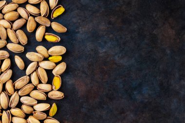 Koyu arkaplanda kavrulmuş fıstık. Pistachio - sağlıklı vejetaryen protein besleyici gıdalar. Sağlıklı atıştırmalıklar. Uzayı kopyala Üst görünüm