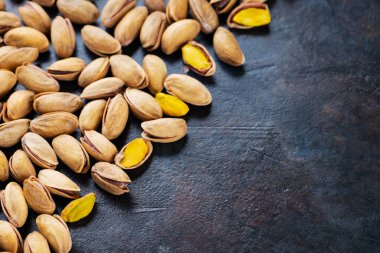 Koyu arkaplanda kavrulmuş fıstık. Pistachio - sağlıklı vejetaryen protein besleyici gıdalar. Sağlıklı atıştırmalıklar. Uzayı kopyala Üst görünüm