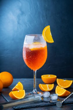 Aperol sprey kokteyli ve bar aksesuarları. İtalyan aperol sprey kokteyli ve koyu arkaplanda dilimlenmiş portakal. Yaz kokteyli aperol spreyini tahtaya serptim.