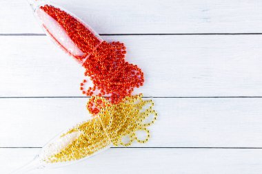 Beyaz arka planda noel boncukları olan şampanya kadehleri. Tahta tahtalarda Noel süsleri. Uzayı kopyala Üst görünüm