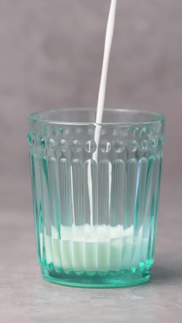 牛奶倒在灰色背景的杯子里 乳制品概念 垂直录像 — 图库视频影像
