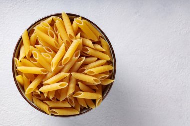 Beyaz desenli arka planda seramik kasede pişmemiş makarna