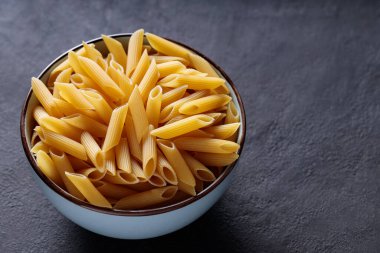 Kasede pişmemiş Penne Makarnası Kara Taş Arka plan Kopyalama Boşluğu