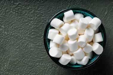 Yeşil desenli yüzey üzerinde turkuaz kasede beyaz şekerlemeler Üst Görünüm Boşluğu Kopyala