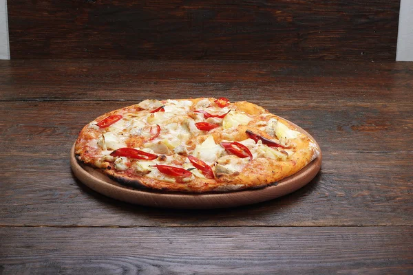 Pizza on a wooden table at which — Stock Photo, Image