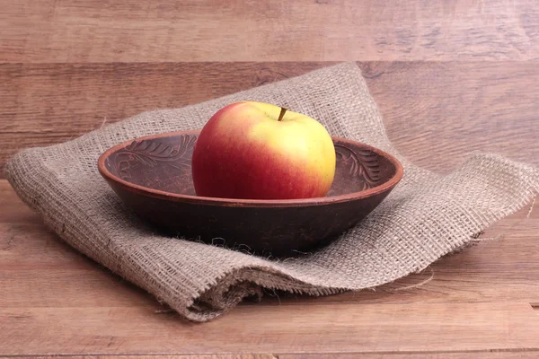 Яблоко на тарелке на деревянном фоне — стоковое фото