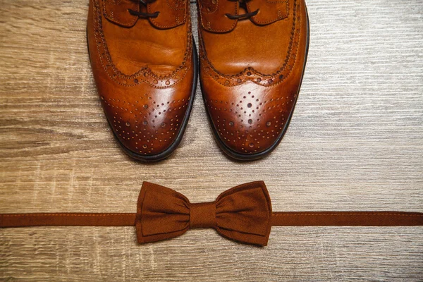 Zapatos masculinos marrones y pajarita marrón en el fondo de madera —  Fotos de Stock