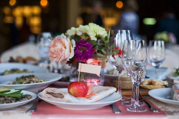 Mooi ingerichte feestzaal tabel met bloemen en verschillende snacks en voorgerechten met broodje, glas wijn, plaat, apple op bedrijfsevenement of huwelijksfeest — Stockfoto