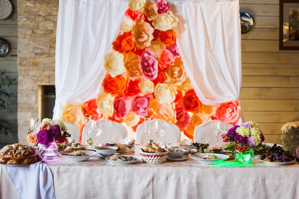 Beautifully decorated presidium table with flowers and different food snacks and appetizers with sandwich, wine glass, plate, apple on corporate event or wedding celebration