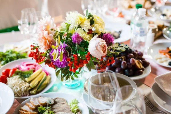 Mesa de banquete lindamente decorada com flores e diferentes lanches e aperitivos de alimentos com sanduíche, copo de vinho, prato, maçã em evento corporativo ou celebração do casamento — Fotografia de Stock