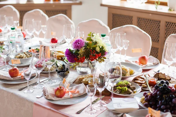 Mesa de banquete bellamente decorada con flores y diferentes aperitivos y aperitivos con sándwich, copa de vino, plato, manzana en evento corporativo o celebración de la boda —  Fotos de Stock