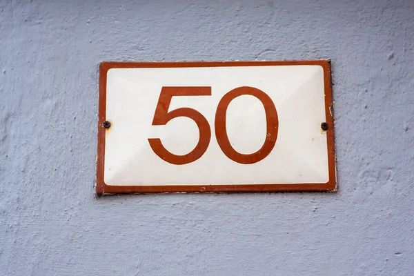 sign with the house number 50 on the stone wall